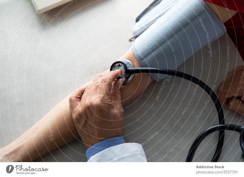 Doctor measuring blood pressure of young patient in clinic doctor man measure stethoscope tonometer coronavirus outbreak physician hospital examine diagnostic