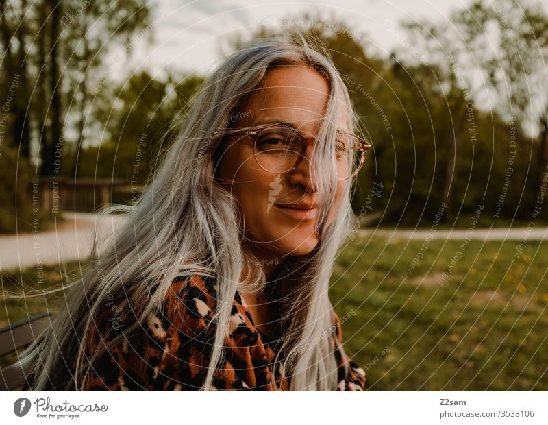 Junge Frau mit Leopardenpulli junge frau lachen lächeln frech brille pullover leopardenmuster sommer sonne wärme grün wiese blond lange haare wind hüsch schön