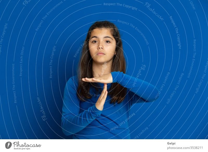 Brunette young woman wearing a yellow T-shirt girl person blue stop rest truce sign break hand time-out down time gesture beautiful female fashion studio hair