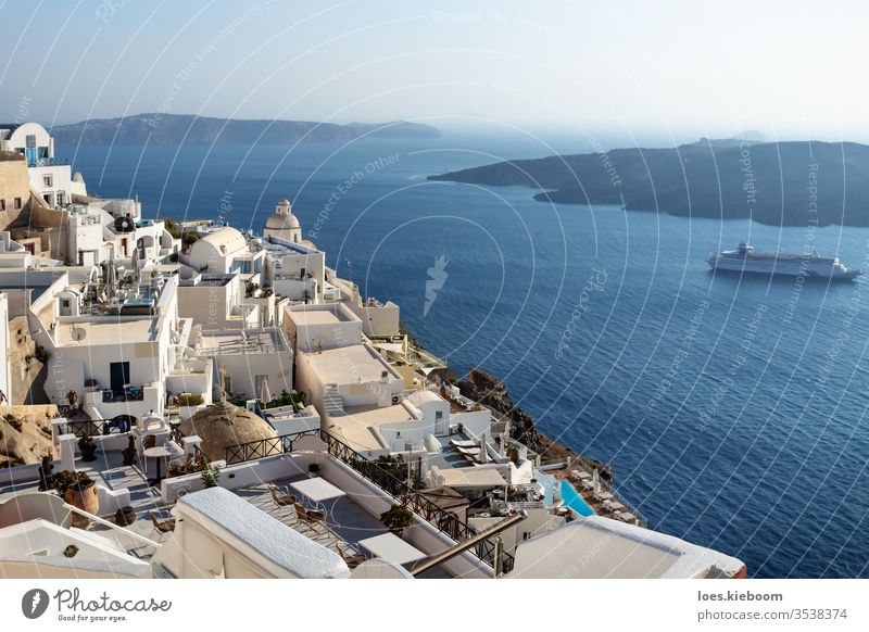 Typical Greek village with church tower far above the sea and passing cruise ship, Fira, Santorini, Greece Mediterranean Cyclades Town Aegean Island