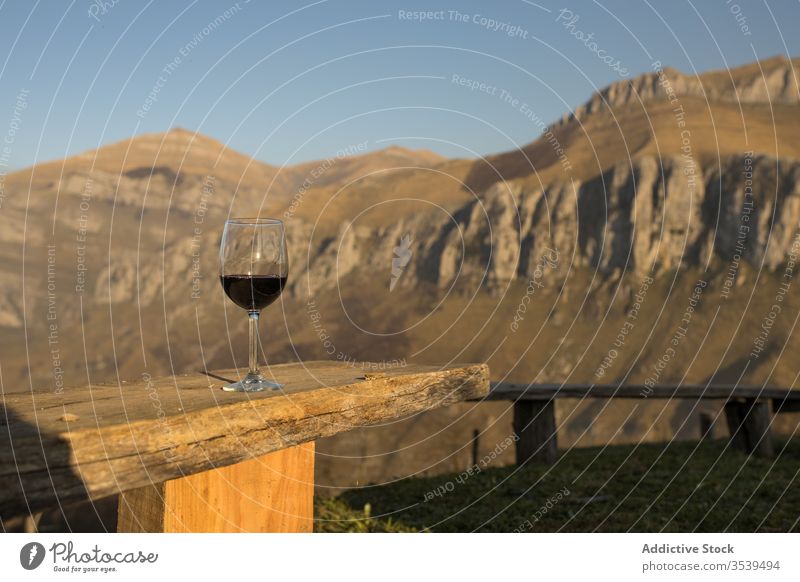 Glass of red wine on wooden railing against countryside mountains nature meadow sunset view idyllic glass beverage alcohol relax landscape peaceful travel