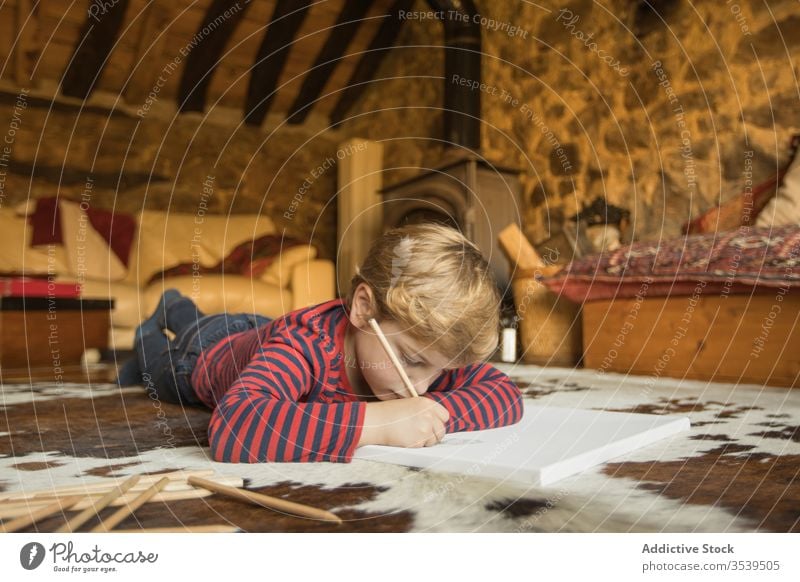 Kid drawing with colored pencils in sketchbook in living room boy house country cabin inspiration nature young carpet spain cantabria stone creative leisure