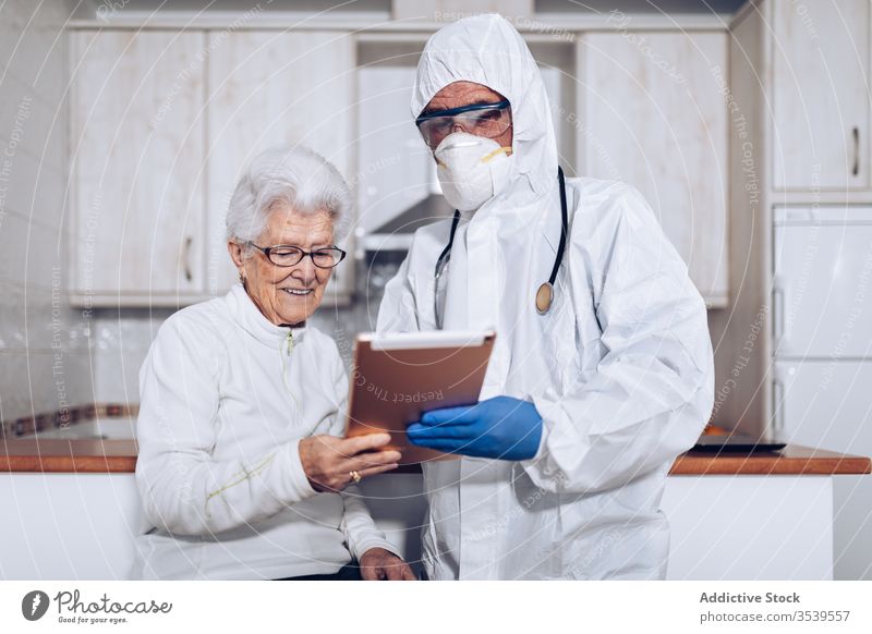 Medical specialist explaining prescription to senior patient during quarantine coronavirus tablet home doctor care medical practitioner health care visit help