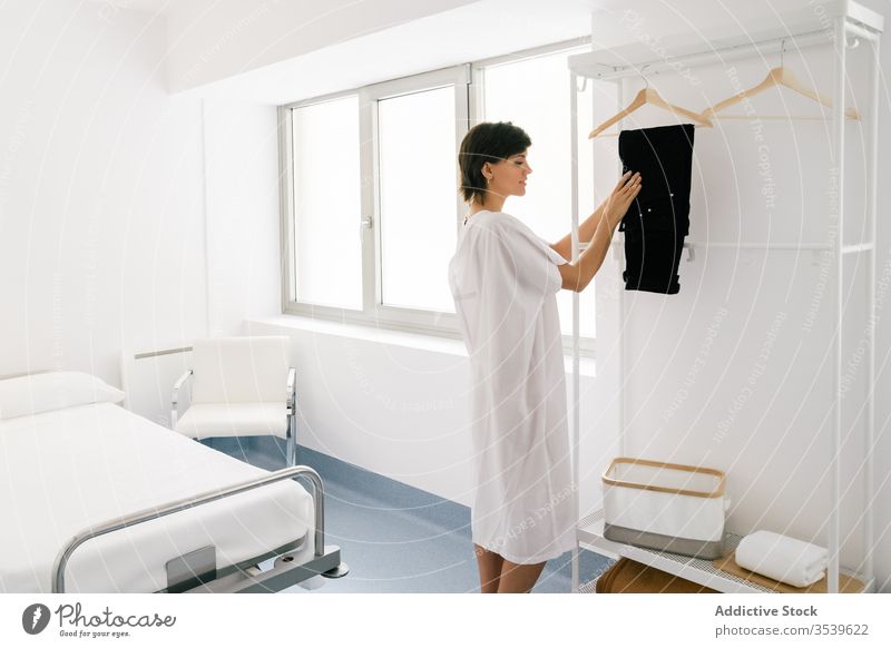 Woman undressing in hospital ward woman hang pants rail happy adult ready female robe procedure medical clinic professional medicine doctor uniform job lady