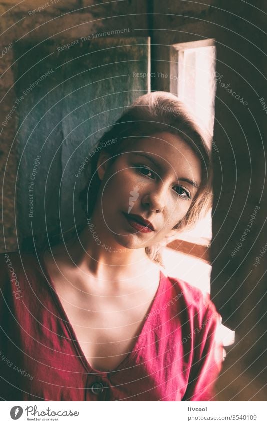 melancholic woman leaning against the window, passing the quarantine at home, in times of covid-19 nostalgically waiting to get out rustic window wooden window