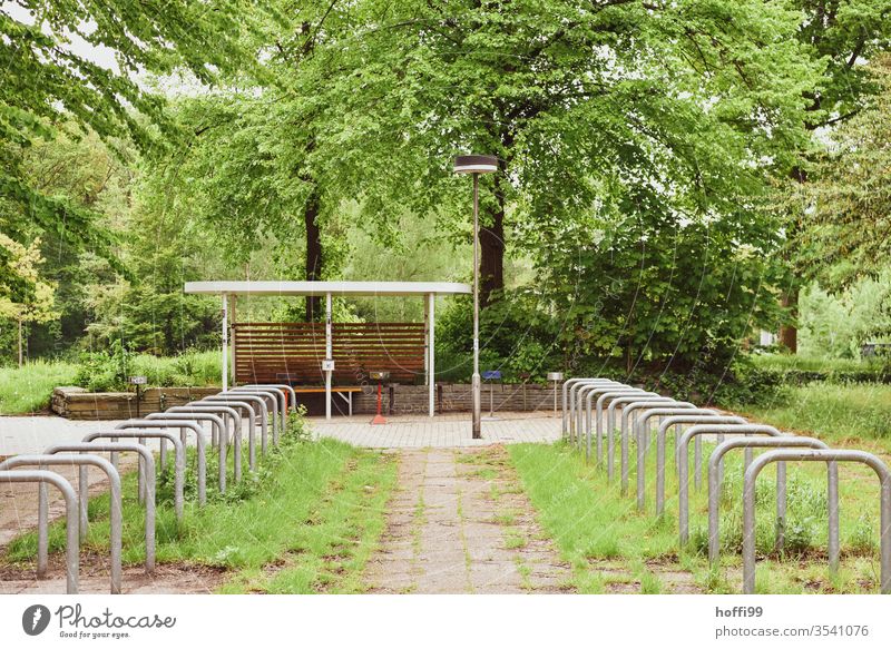 empty bicycle racks in the courtyard surrounded by lush green Bicycle rack "Bicycle stand bicycle holder Bicycle lot wheel stand Parking lot parking space