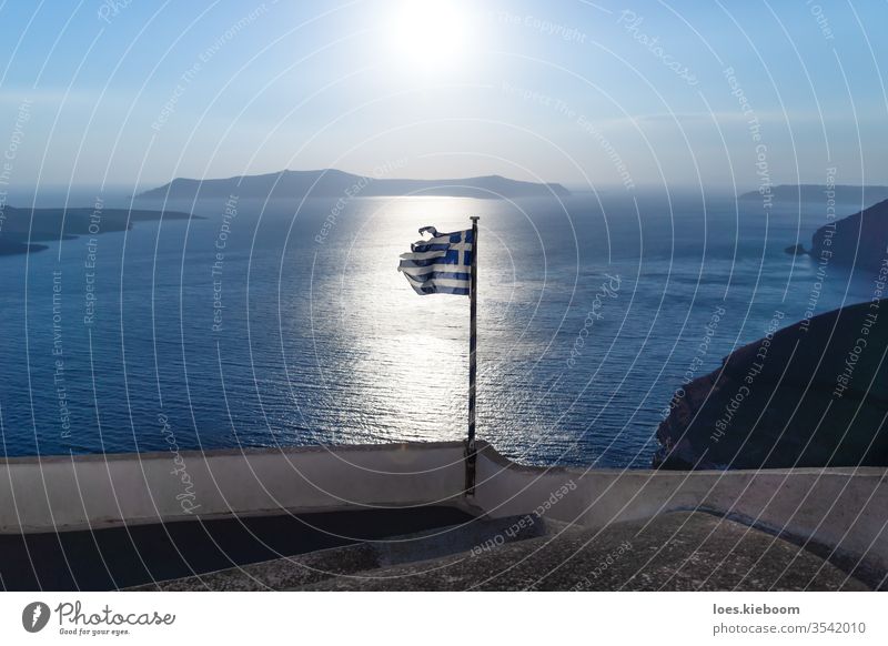 Greek torn flag on backlight of the shining ocean of last sun, Santorini, Greece greece greek sunset broken santorini island sea summer aegean travel cyclades