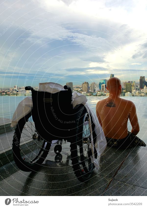 Wheelchair users enjoy the evening atmosphere at the Infinity Pool above the rooftops of Bangkok wheelchair users Handicapped Human being Exterior shot Mobility