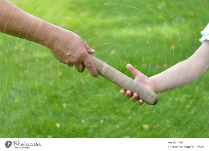 taken literally | passing the baton to the next generation - hand of a mother passes the baton to her child, the daughter passes it on in an outdoor race Rod