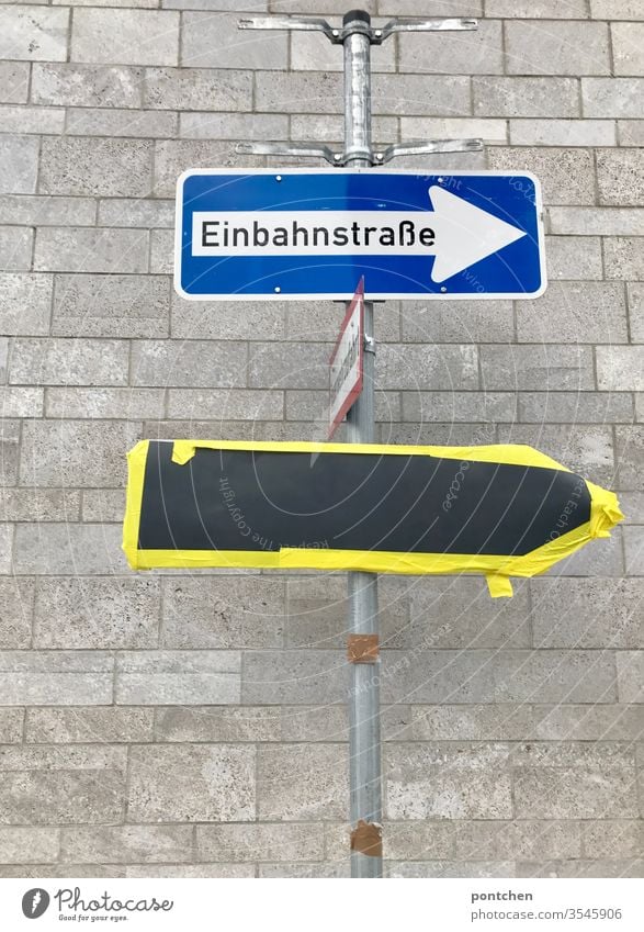 Street sign One-way street attached to a pole. Underneath hangs a glued sign. Construction site. Traffic situation Road sign Signs and labeling Signage masked