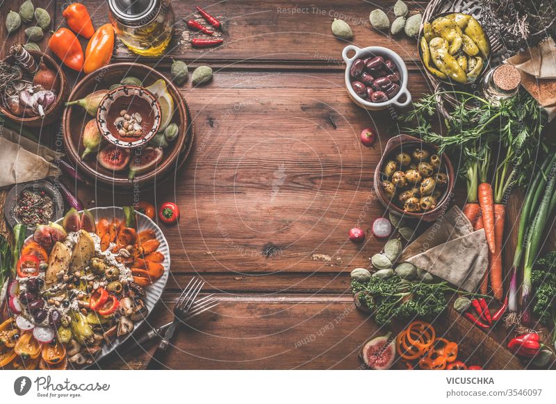 Healthy vegan or vegetarian food background with snacks. Various fresh, pickled and fermented vegetables in bowls. Hummus plate with roasted vegetables and nuts. Olives, figs, green almond , chickpeas