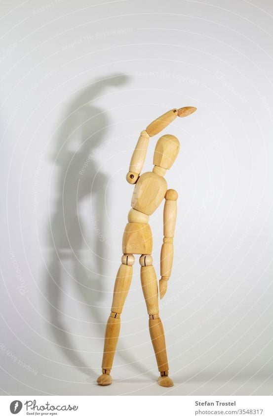 wooden doll during yoga practice Ansanas, triangle Trikonasana, in front of white background body dummy balance figurine fitness gesture sample model isolated