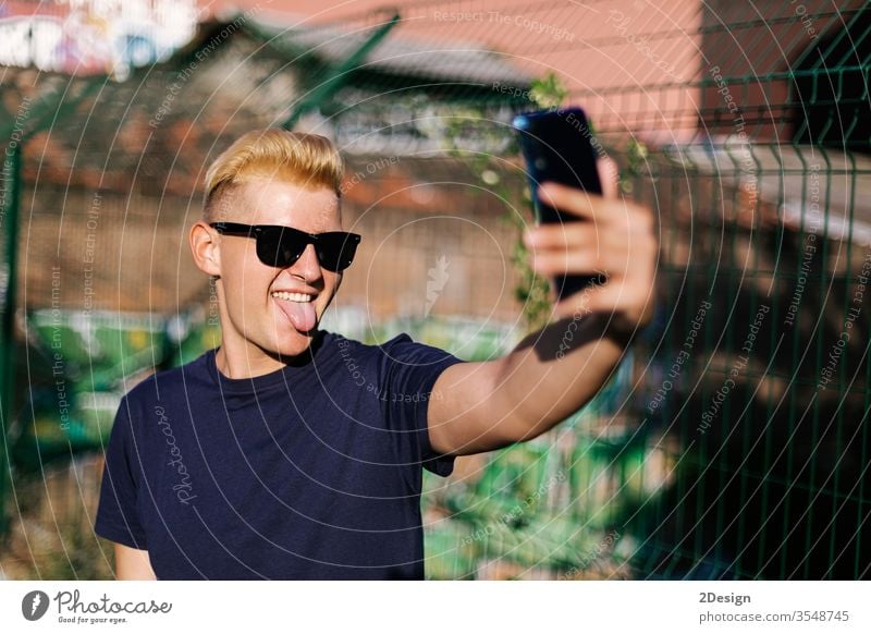 Young teenager with sunglasses taking a selfie outdoors male young phone 1 man person using portrait smartphone modern holding lifestyle people caucasian