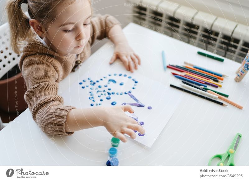 From above of little girl using gouache for drawing with fingers on paper at home child paint kindergarten creative kid cute education pencil learn elementary