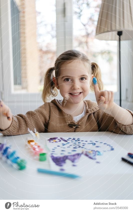 Little girl showing finger with gouache while drawing in living room paint paper point playful cute preschool abstract picture creative kid child inspiration