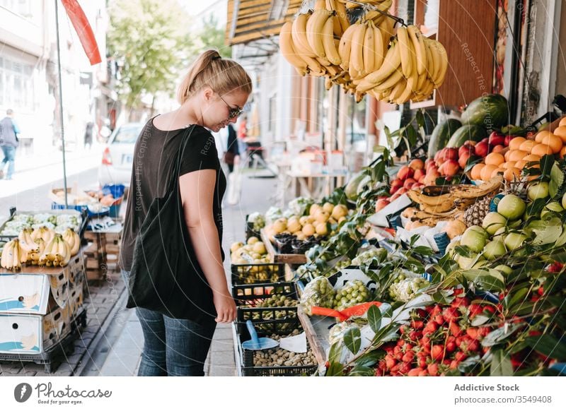 Woman choosing fruits in local market woman counter bazaar street colorful choose goods explore walk city lifestyle buyer shopper sunglasses outdoors customer