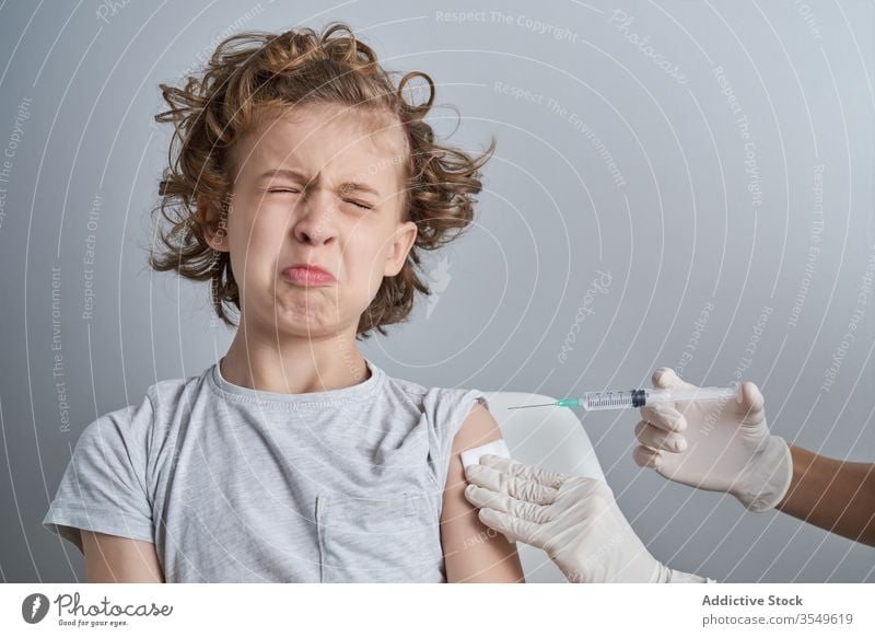 Anonymous doctor holding boy shoulder during injection in clinic vaccine treat syringe medicine glove patient health care procedure work healthy cure kid tool