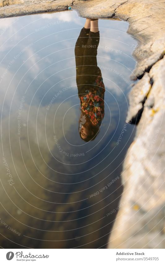 Reflection of woman in water of lake reflection stone puddle sun tourism daytime nature upside down clear stand freedom surface idyllic travel journey shore