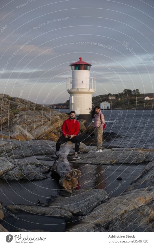 Couple standing on stones near lake with observation tower couple river travel lakeside hill cloudy sky explore relationship vacation rest tourism weekend