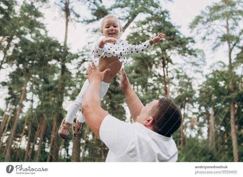 The father throws up and spins the daughter on nature on summer day vacation. Dad and girl playing in the park at the sunset time. Girl flying. Concept of friendly family. Closeup. selective focus