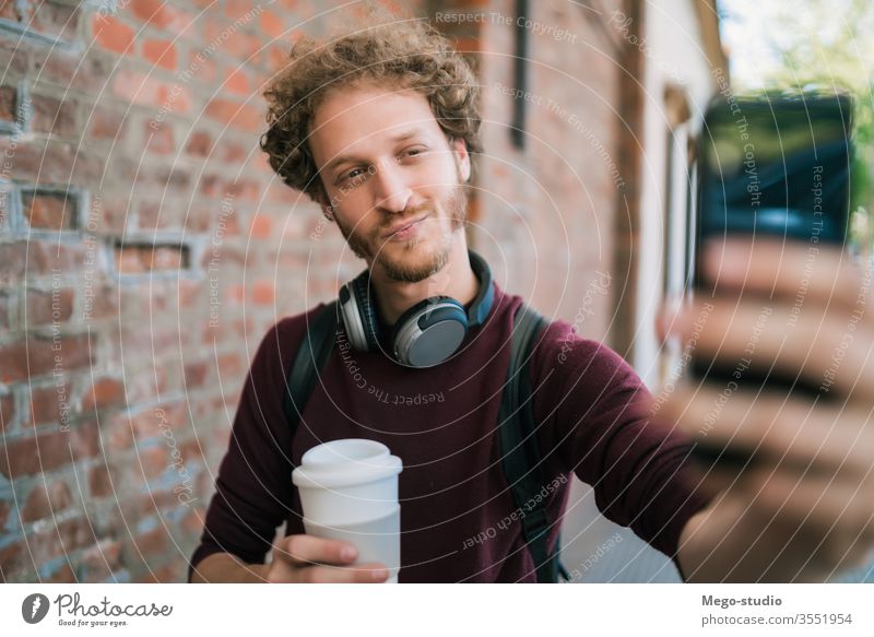 Young man taking selfies with phone. male outdoor young smile people street holding cellphone mobile city urban guy make face casual take photo use clothing