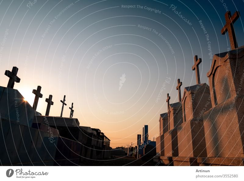 Cemetery or graveyard in the evening with sunset sky. Headstone and cross tombstone cemetery. Rest in peace. Funeral concept. Sadness, lament, and death background. Walkway between burial ground.