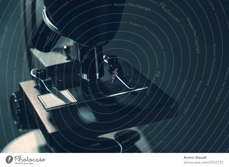 details of a silver microscope, with black background analyzing biology biotechnology brightly lit chemistry close-up closeup discovery education equipment