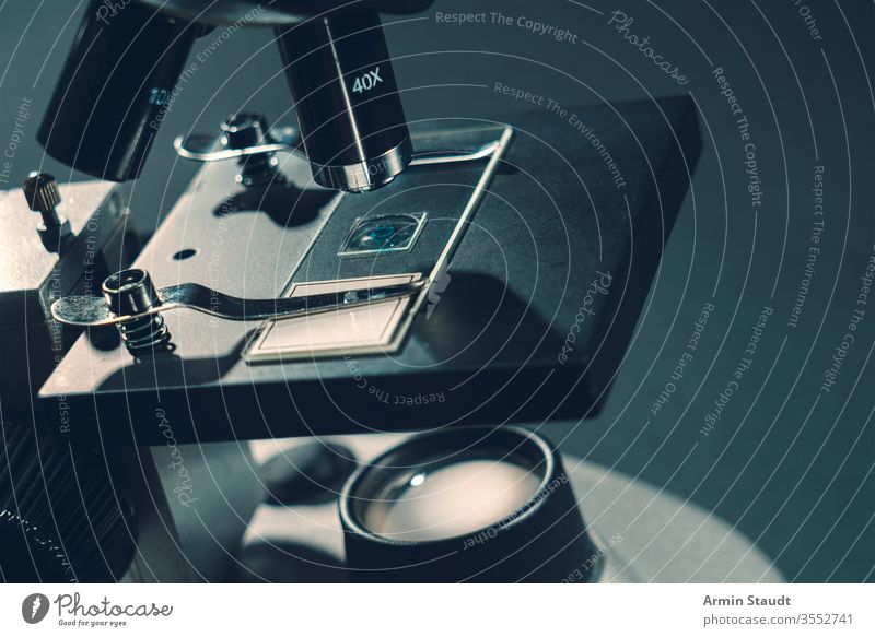 details of a silver microscope, with black background analyzing biology biotechnology brightly lit chemistry close-up closeup discovery education equipment