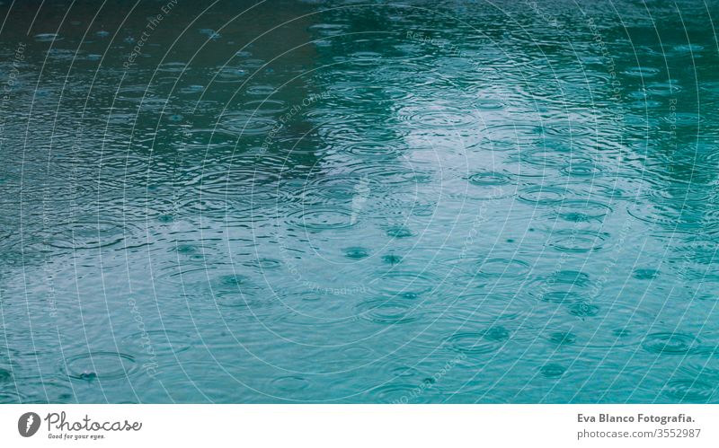 Round droplets of water over the circles on the water. Water rain drop, whirl and splash. Ripples on pool texture pattern background. Desktop or laptop wallpaper. Closeup water rings affect the surface.