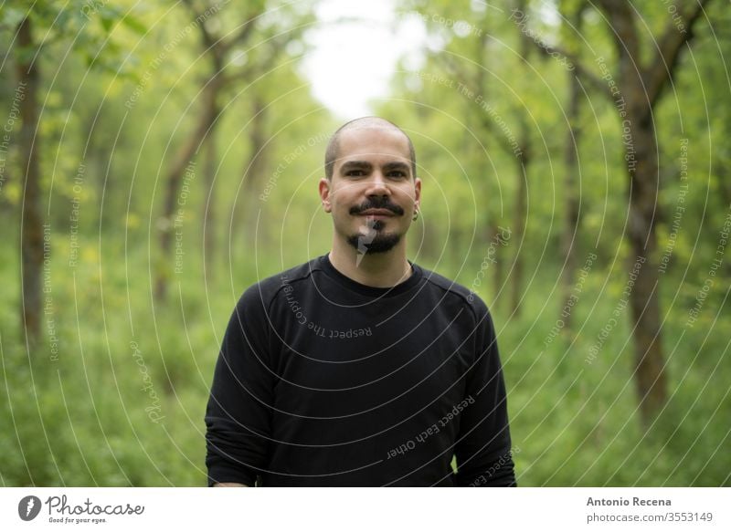 Man in forest portrait smiling and looking at camera Bald man hike outdoors tree person handsome male adult 30s 40s goatee facial hair shaved head skin head men