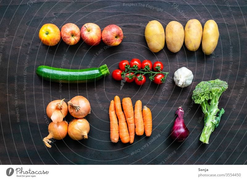 Fresh regional vegetables in a row on a brown wooden background, top view Vegetable variegated regionally vegetable box Food Organic produce Vegetarian diet