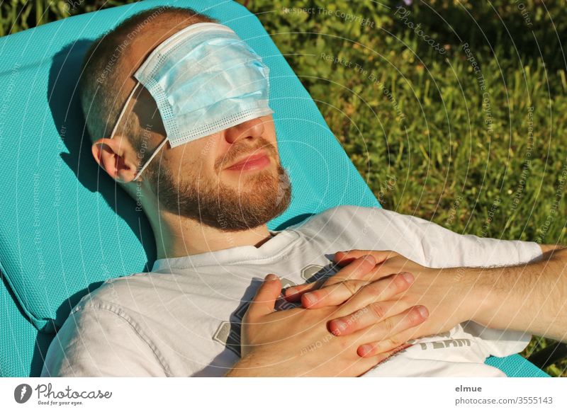 young man lies on a sun lounger and has a breathing mask in front of his eyes Respirator mask Face mask Eye protection hygiene sun protection Precuation peril