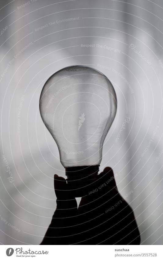 female hand holding an old light bulb by hand feminine Fingers fingernails Electric bulb Glass Transparent Bright conceit Light and shadow outline in the shade