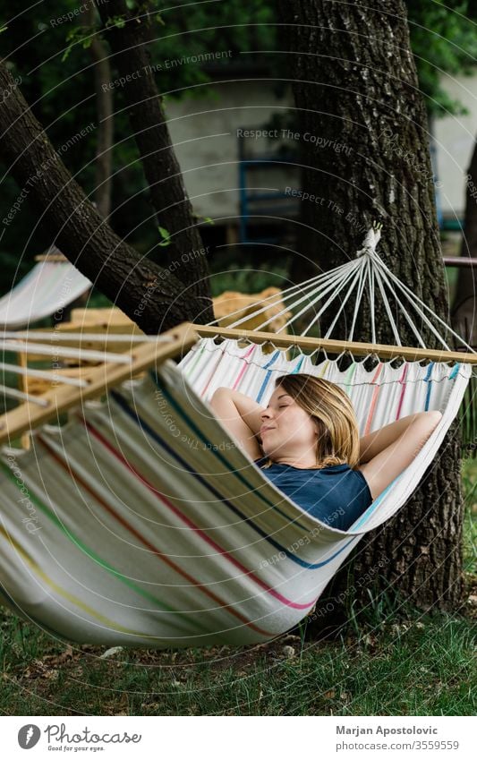 Young woman relaxing in the hammock in nature adult alone backyard calm carefree casual comfortable countryside day dream easy enjoy female forest furniture