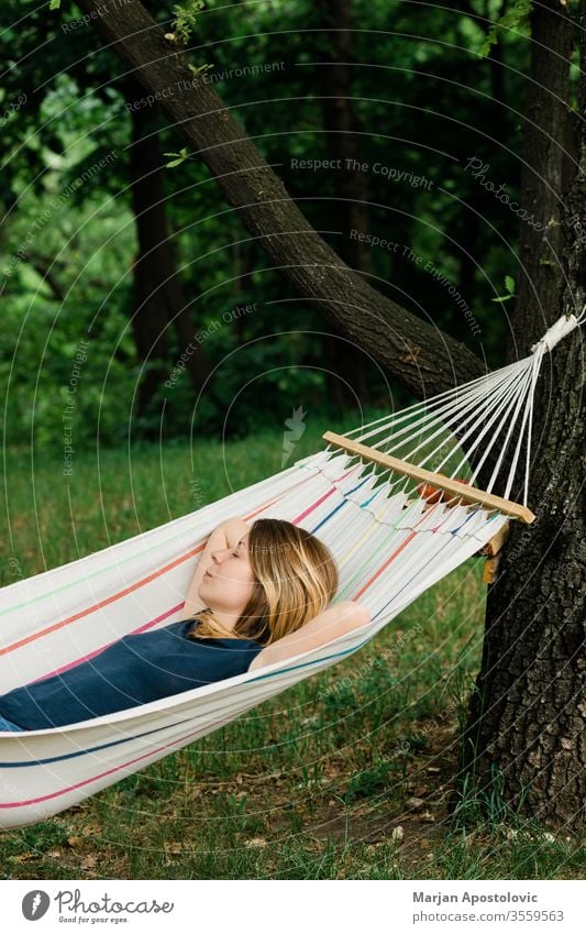 Young woman relaxing in the hammock in nature adult alone backyard calm carefree casual comfortable countryside day dream easy enjoy female forest furniture