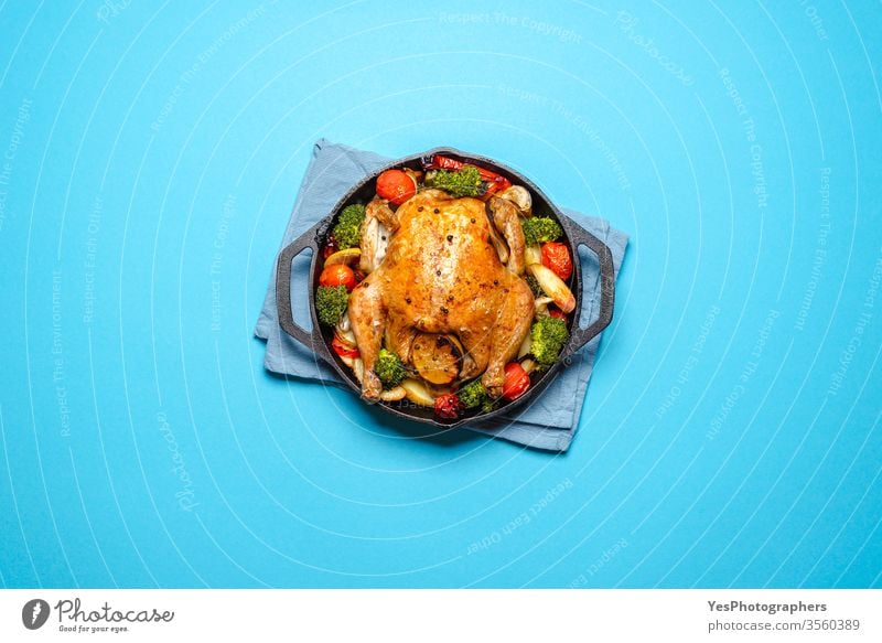 Roasted chicken with vegetables in an iron cast, top view. above view baked blue background broccoli christmas cook cooked copy space crispy cuisine diet dinner