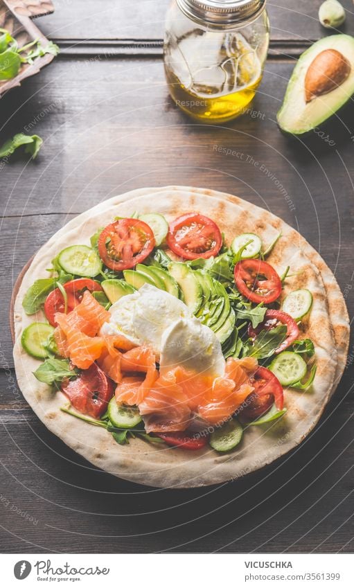 Tortilla with salmon,avocado, cheese, arugula, tomatoes and cucumbers. Flat bread with ingredients . Wrap preparation. tortilla flat bread wooden table wrap