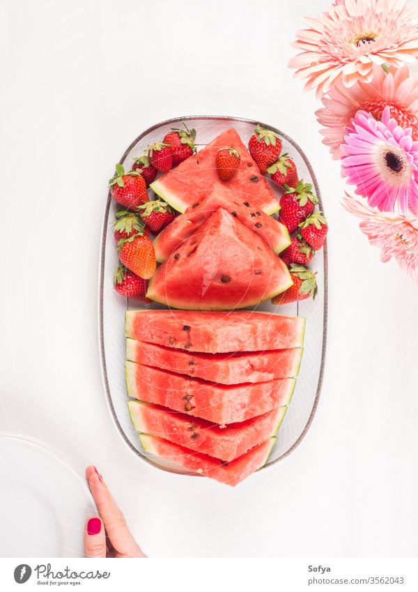 Watermelon slices on tray on white wooden table watermelon summer strawberries ceramic hands pink female fresh snack flowers delicious beautiful bright eat food