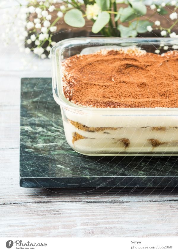 Traditional coffee tiramisu dessert in glass dish cocoa mascarpone traditional food powder home made sweet italian container green marble board treat festive