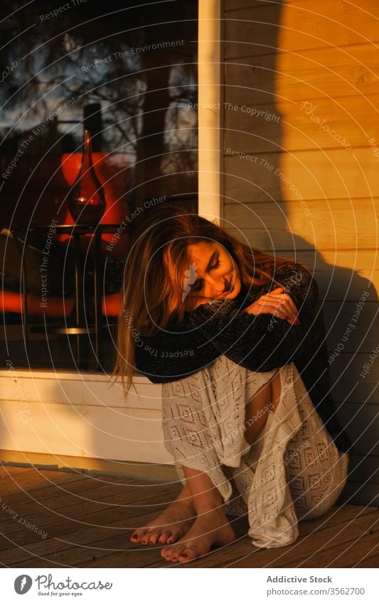 Delighted woman admiring sunset on terrace of wooden cabin admire relax veranda house delight barefoot female serene chill weekend countryside casual outfit