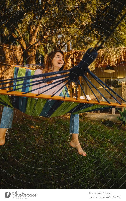 Relaxed woman in hammock in the sunset relax calm smiling happy lying courtyard enjoy female summer holiday vacation weekend casual outfit lady rest peaceful