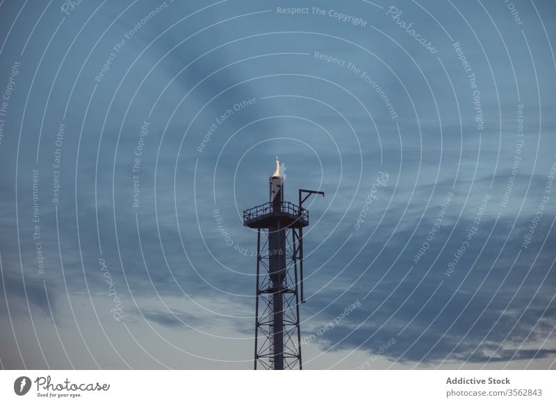 Gas flaring at oil refinery in evening gas flare stack petroleum flame burn blaze fire bright illuminate industrial landscape area fuel heat hot dusk twilight
