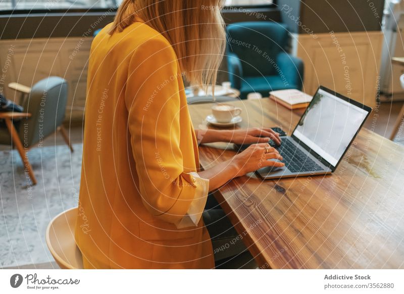 Adult woman drinking aromatic coffee while working on laptop in coffee shop freelance using cafe foam internet latte cup home beverage cappuccino surfing