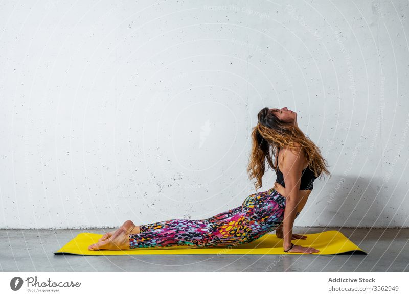 Woman practicing yoga on mat woman practice upward facing dog pose bhujangasana posture position balance eyes closed flexible concrete activity wall modern