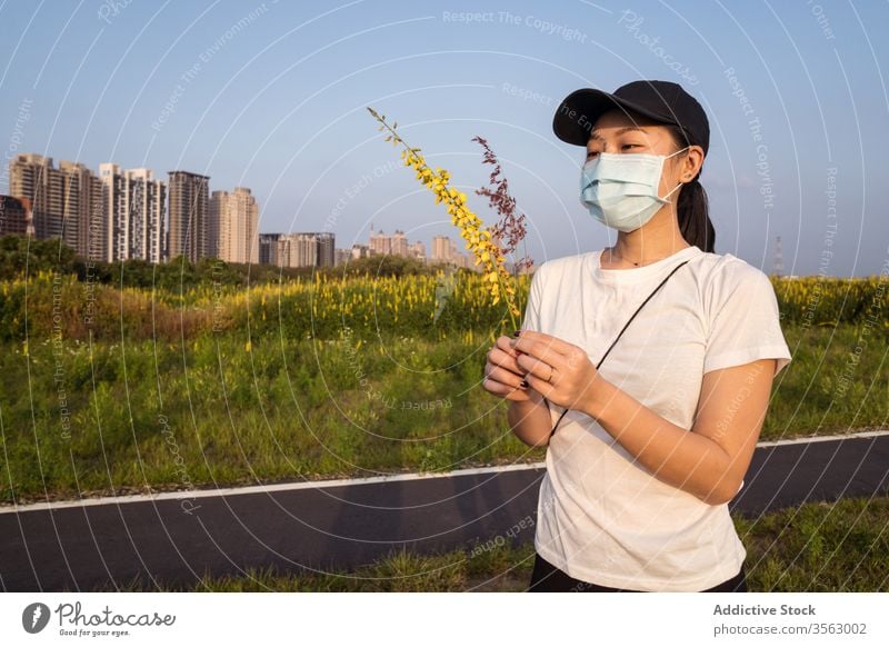 Ethnic woman in medical mask standing on green field protect coronavirus prevent covid nature young casual ethnic female modern safety health care covid 19