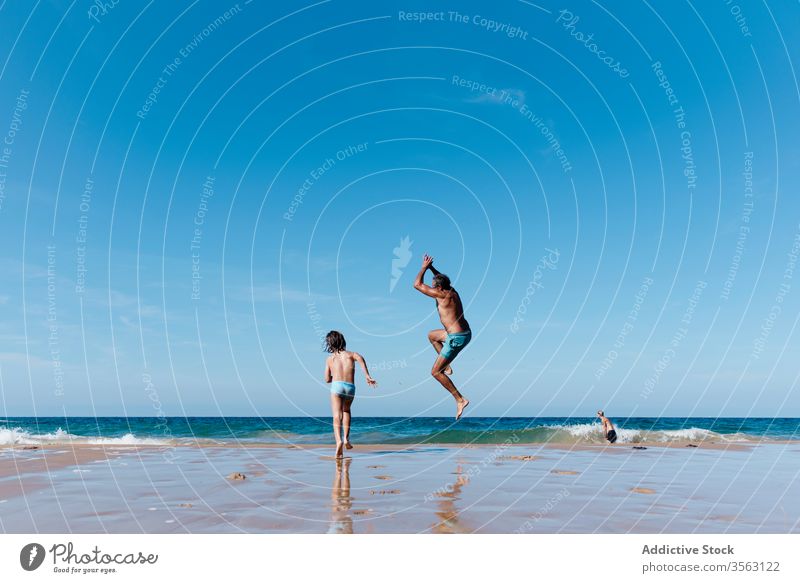 Father and kid having fun on beach father sea jump together happy vacation holiday man water summer run sand ocean coast shore child joy nature carefree