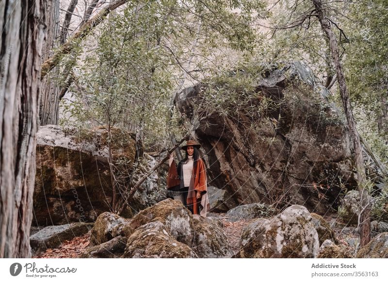 Young woman standing near large stones in forest rock boulder travel trendy style tree landscape yosemite park boho rustic united states mountain national