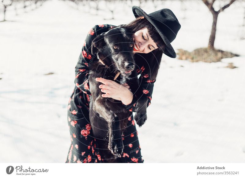 Stylish woman with dog in winter field style trendy snow black together pet female fashion park relax forest tree calm hat breed cold sun owner beautiful cloth