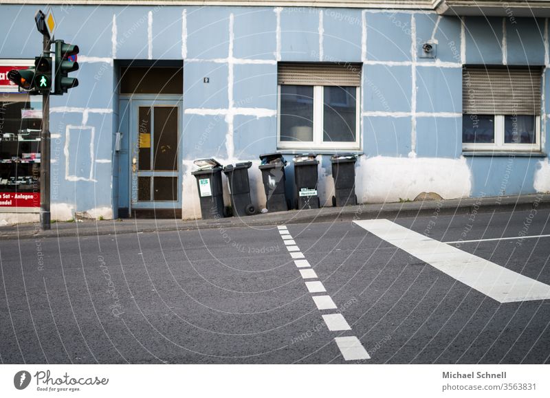 Pedestrian crossing with traffic lights leading to an insufficiently renovated house, with garbage cans in front of it Traffic light Intersection