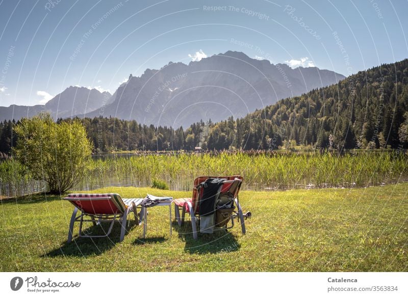 The mountain scenery, the deck chairs on the lawn, the lake and the beautiful weather are waiting for guests deckchairs Lake Lakeside Juncus reed mountains Alps